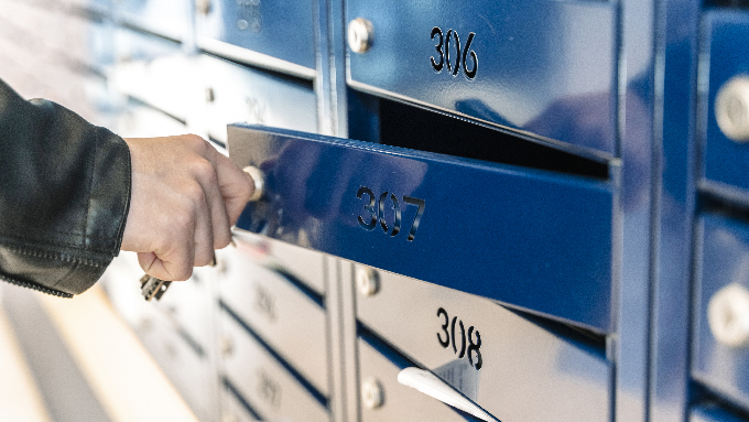eine männliche person öffnet einen briefkasten